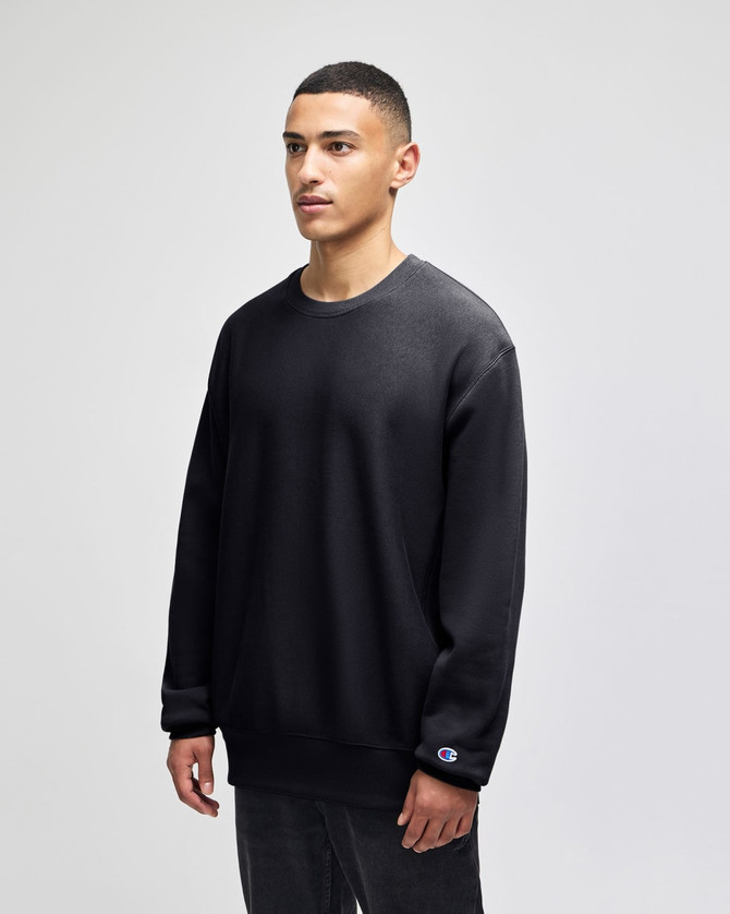 A black Champion Reverse Weave® adult crew sweatshirt displayed on a model, featuring a logo on the sleeve.
