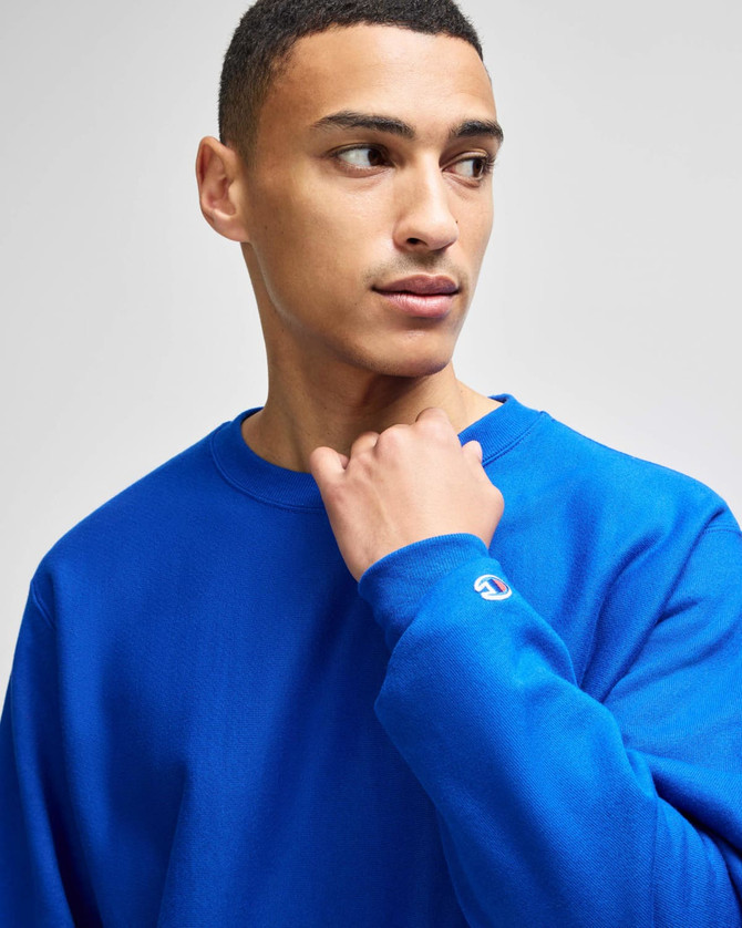 A blue Champion Reverse Weave® adult crew sweatshirt featuring a logo on the sleeve.