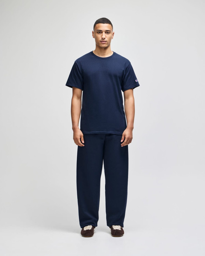 A model wears navy Champion Powerblend® adult open-bottom fleece pants with pockets, paired with a matching t-shirt.