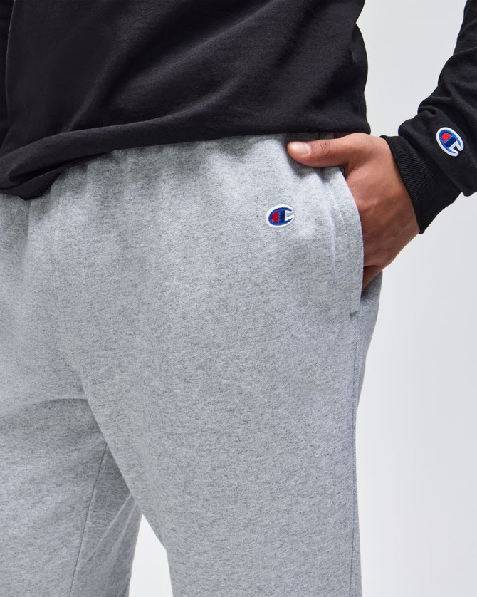 A pair of grey fleece joggers with a logo, featuring side pockets and an elastic waistband.