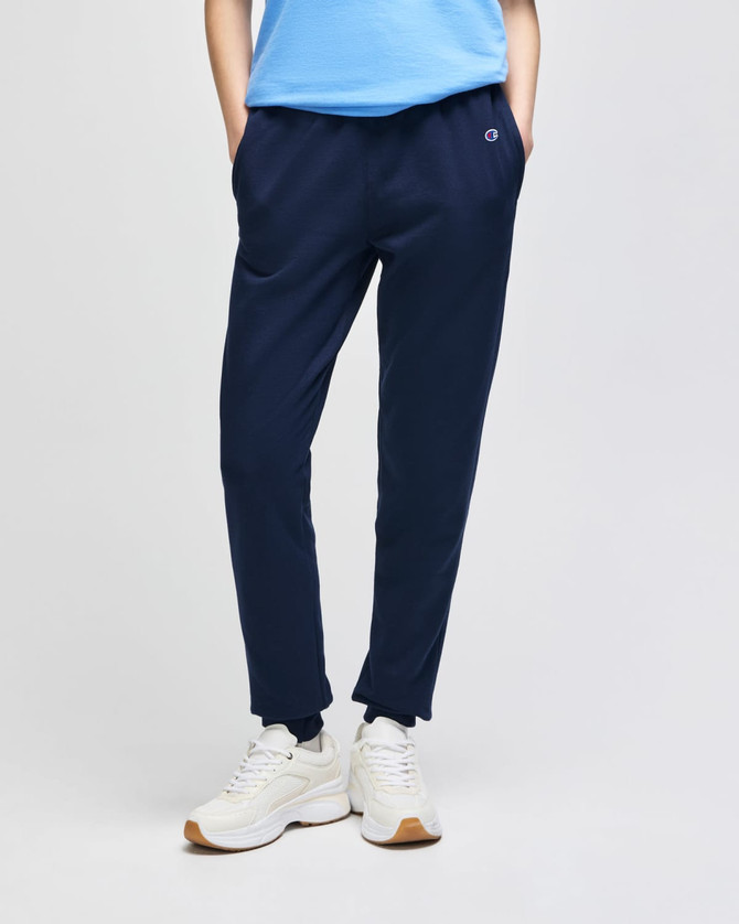 Navy fleece jogger pants with pockets, featuring a logo. Worn with white sneakers and a blue top.