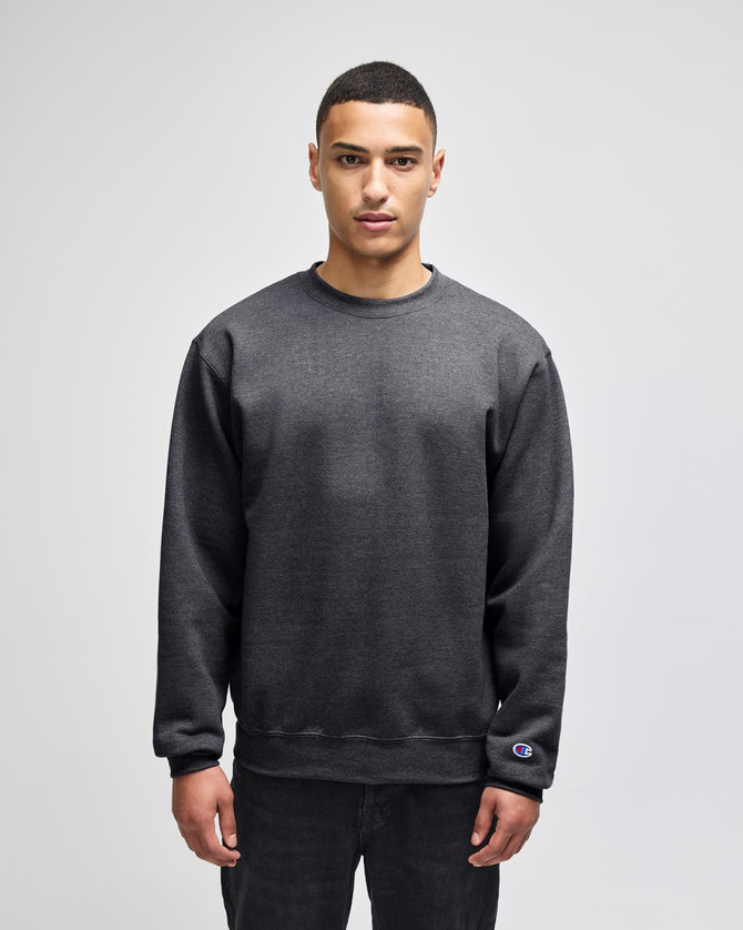 A grey adult crewneck sweatshirt featuring a logo, modelled by a person standing straight.