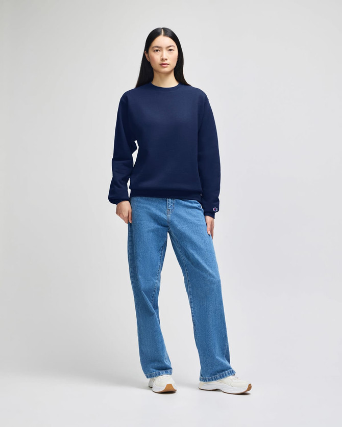 A navy blue crewneck sweatshirt featuring long sleeves and a logo, paired with light blue jeans.
