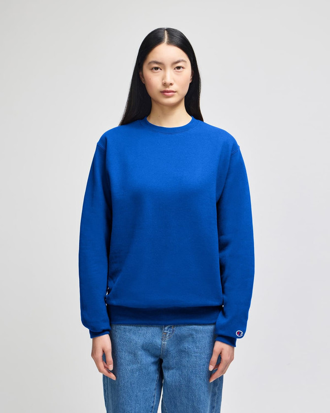 A vibrant blue crewneck sweatshirt is worn by a model, featuring a logo on the sleeve.