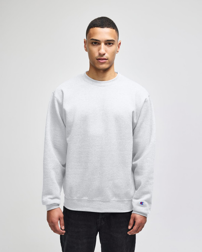 A grey crewneck sweatshirt displayed on a model, featuring a logo on one sleeve.