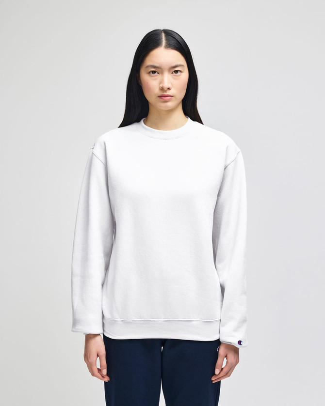 A white crewneck sweatshirt made from Champion Powerblend® fabric, featuring a logo on the sleeve.