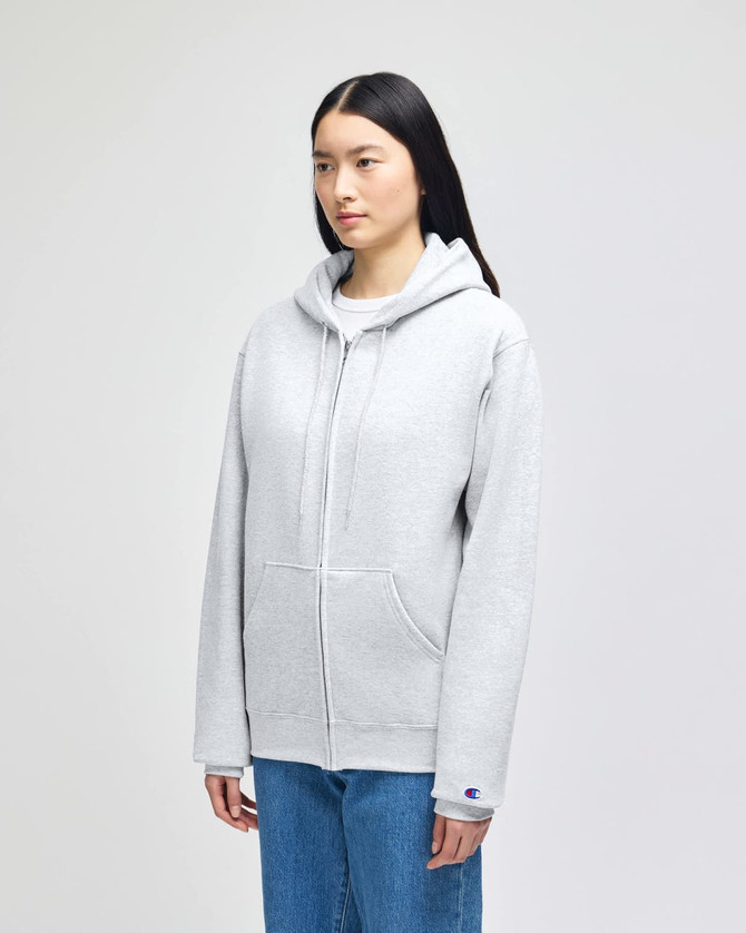 A grey full-zip hooded sweatshirt with a front pocket and a logo on the sleeve, displayed on a model.
