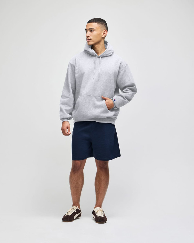 A grey hooded sweatshirt with a front pocket, paired with navy shorts and brown shoes, featuring a logo.