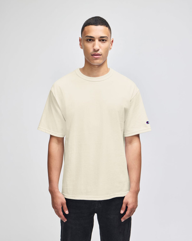 A beige Champion Adult Heritage Jersey T-Shirt displayed on a model, featuring a simple design and short sleeves.
