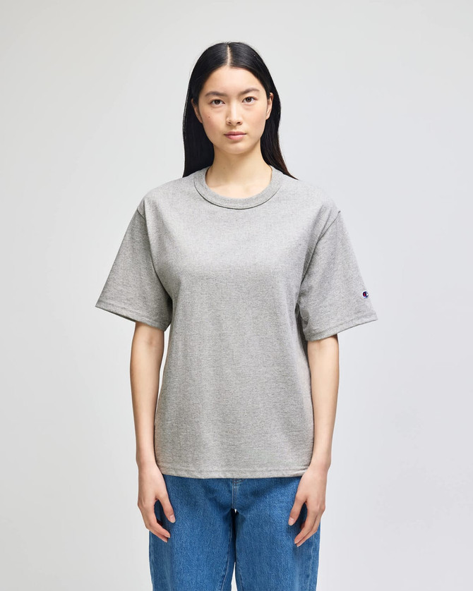 A grey Champion Adult Heritage Jersey T-Shirt on a model, featuring a relaxed fit and short sleeves.