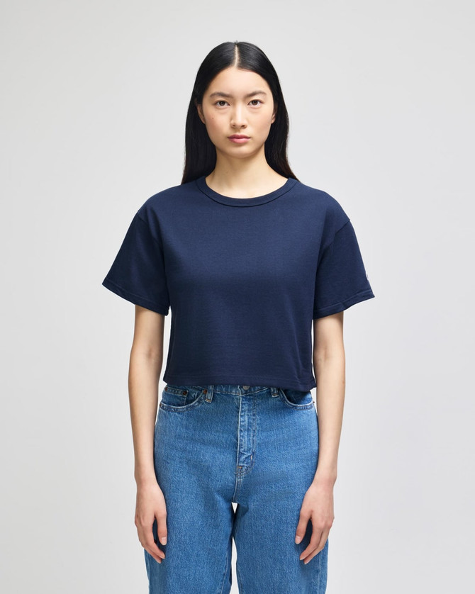 A cropped short sleeve t-shirt in navy blue with a relaxed fit, featuring a logo on the front.