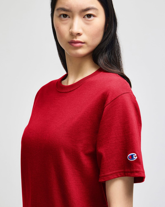 A red short-sleeve t-shirt with a logo on the sleeve, displayed on a model.