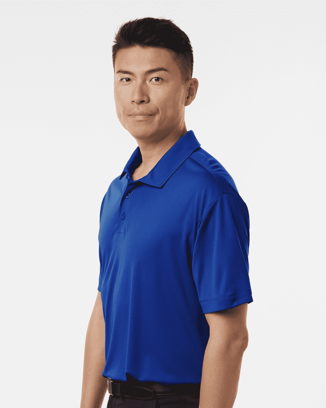 A man wearing a blue polo shirt, featuring a logo on the chest, stands in a neutral pose.