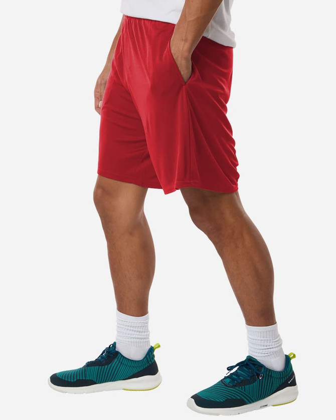 Men's performance shorts in red, featuring side pockets, paired with athletic shoes in teal and black.
