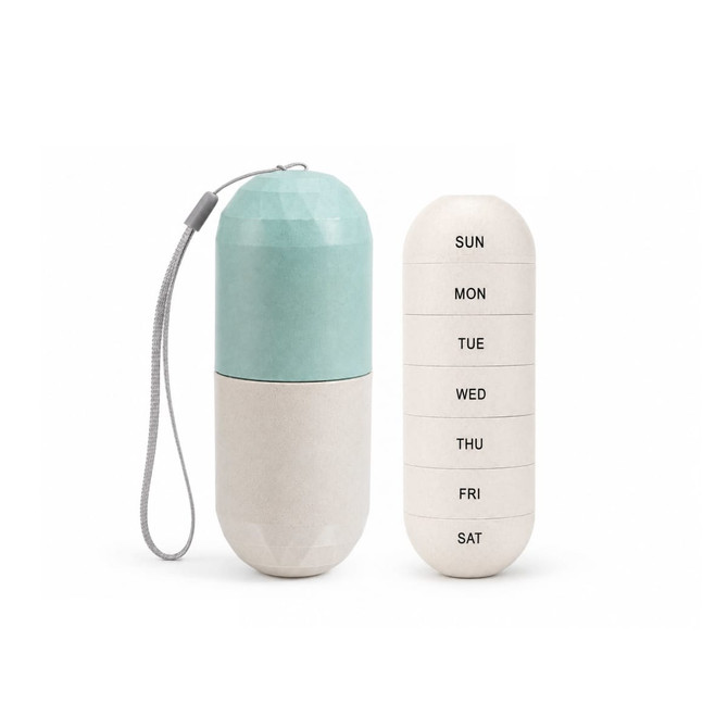 A capsule-shaped pill organiser in green and beige, with seven compartments labelled for each day of the week.