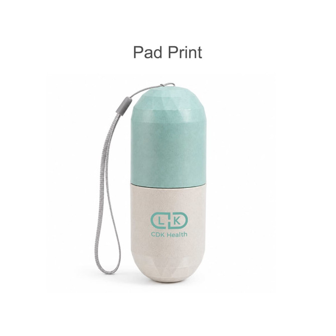 A capsule-shaped pill organiser in mint green and beige, featuring a logo and a grey strap for easy carrying.