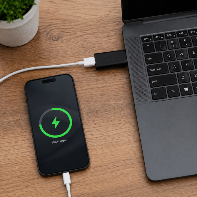 A black USB data blocker connects a smartphone to a laptop, displaying a charging graphic on the phone.