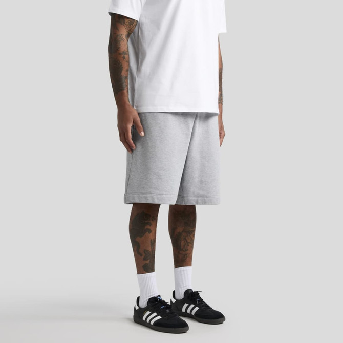 Grey shorts with a relaxed fit, paired with a white T-shirt and black sneakers. Features visible tattoos on the legs.