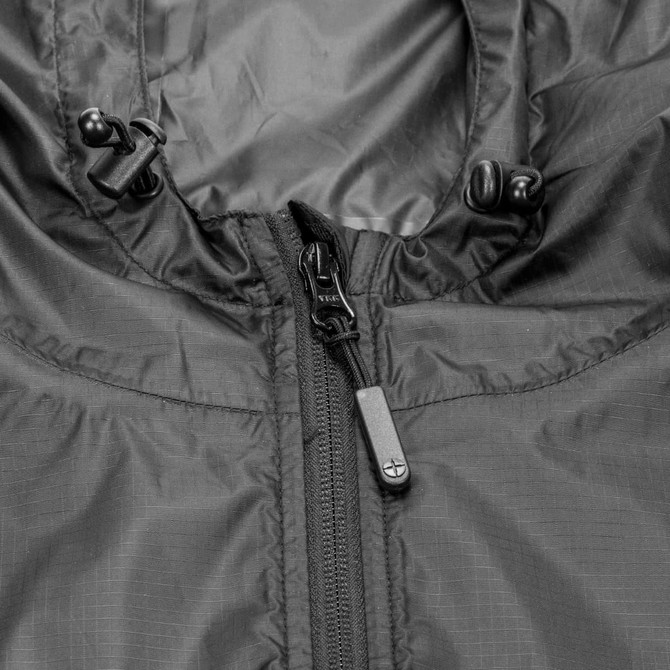 A close-up of a black windbreaker jacket featuring a zip and adjustable cords on the hood, with a logo.