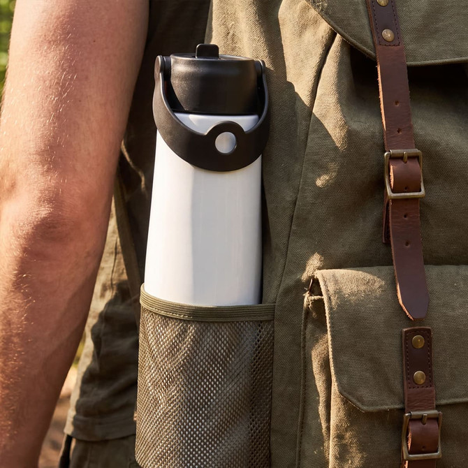 A drink bottle with a black lid and a white body, stored in a green mesh side pocket of a bag.
