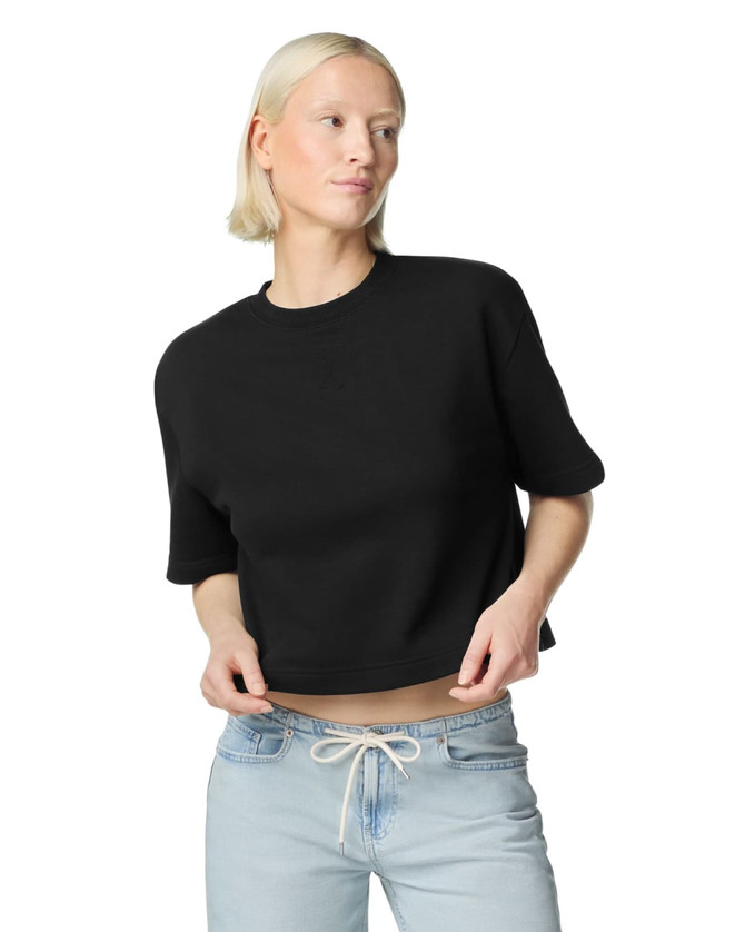 A black mid-length boxy top with short sleeves, styled with light blue jeans. The fabric appears soft and textured.