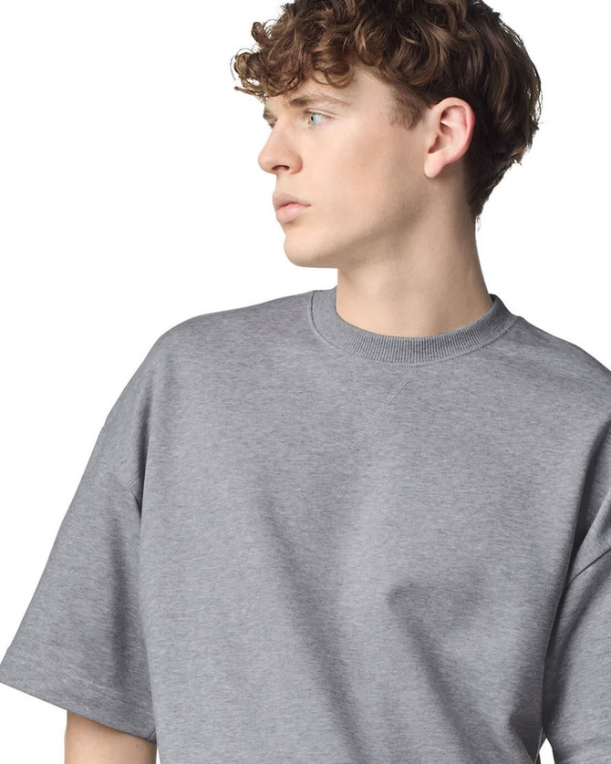 A grey unisex oversized boxy top with a round neckline and short sleeves, featuring a logo.