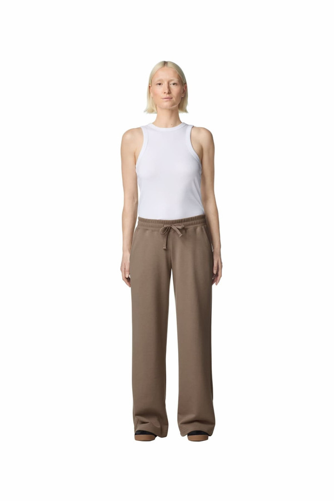 Wide leg pants in a beige colour, worn by a model with a white tank top. The pants feature a drawstring waist and have a logo.