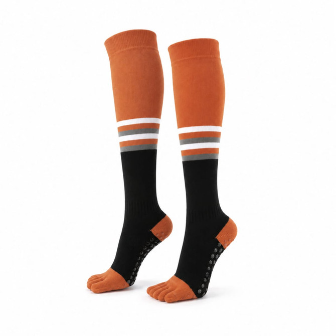 Knee-high socks in orange and black with white and grey stripes, featuring grip dots on the soles.