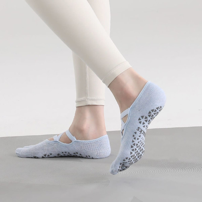 A pair of light blue yoga toe socks with a textured grip sole, worn by a person in fitted pants.