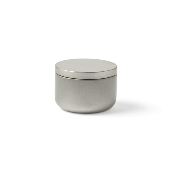A silver mini tin candle with a lid, featuring a smooth metallic finish and a round shape.