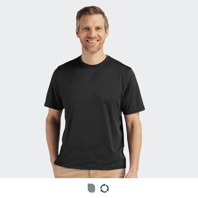A man wearing a black tee shirt, smiling against a light grey background. The tee has a logo.