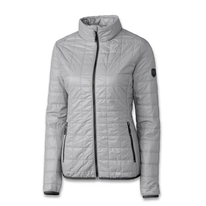 A light grey women's jacket with a quilted design, featuring a zip front and side pockets. It has a logo on the sleeve.