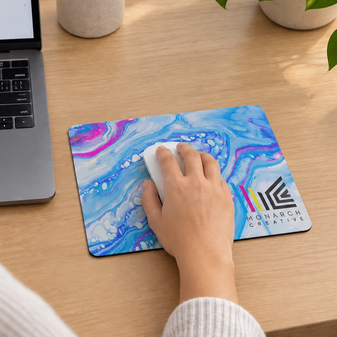 A colourful mouse mat with a blue and purple marbled design, featuring a logo in the bottom corner and a mouse on top.