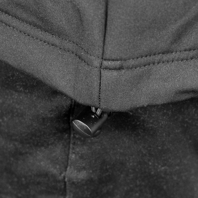 A close-up of the zippered neckline on a black soft shell jacket, featuring a pull tab and stitched detailing.