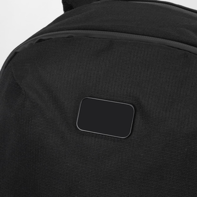 A black backpack with a textured surface and a small, blank rectangular area. It features a logo or branding.