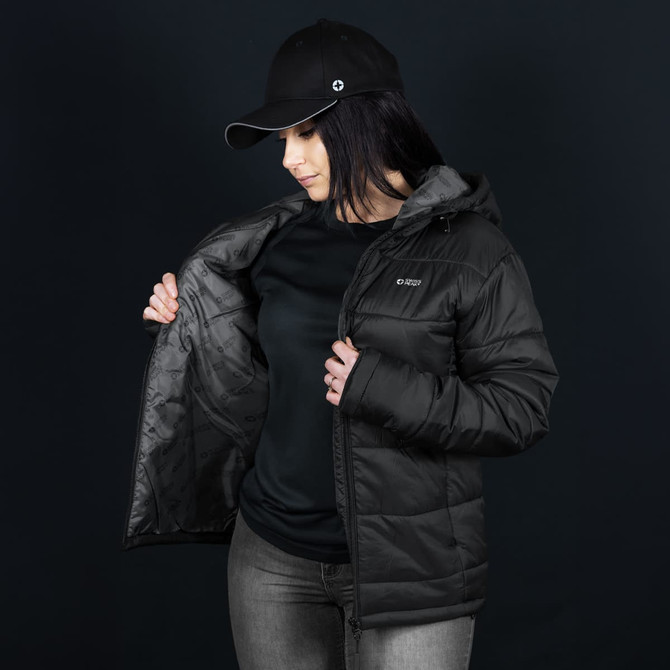 A woman in a black puffer jacket with a hood, wearing a black cap. The jacket features a logo and is partially unzipped.