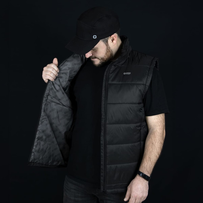 A man in a black Swiss Peak Urban Puffer Vest, holding it open to display the interior lining.