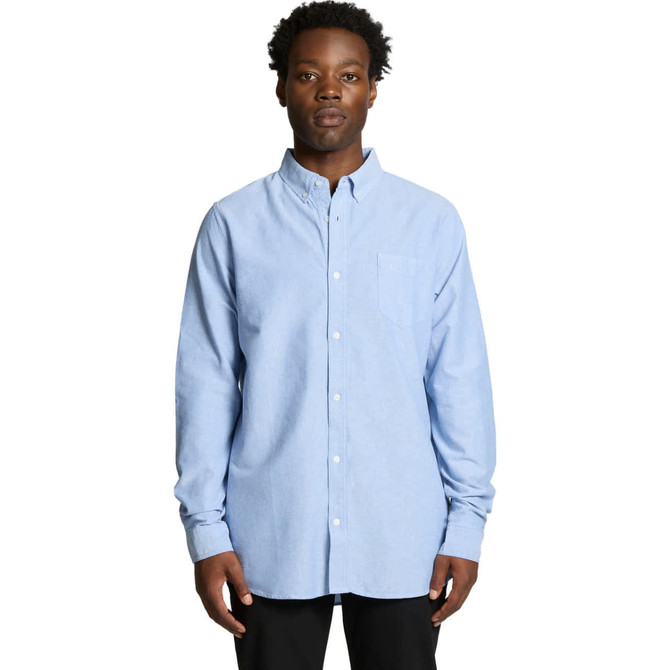 A blue button-up Oxford shirt featuring a collar and a chest pocket, worn by a model.