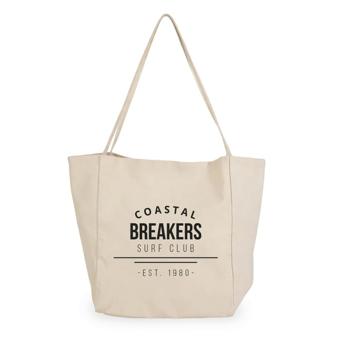 A cream tote bag with a logo featuring the text "Coastal Breakers Surf Club" and a date.