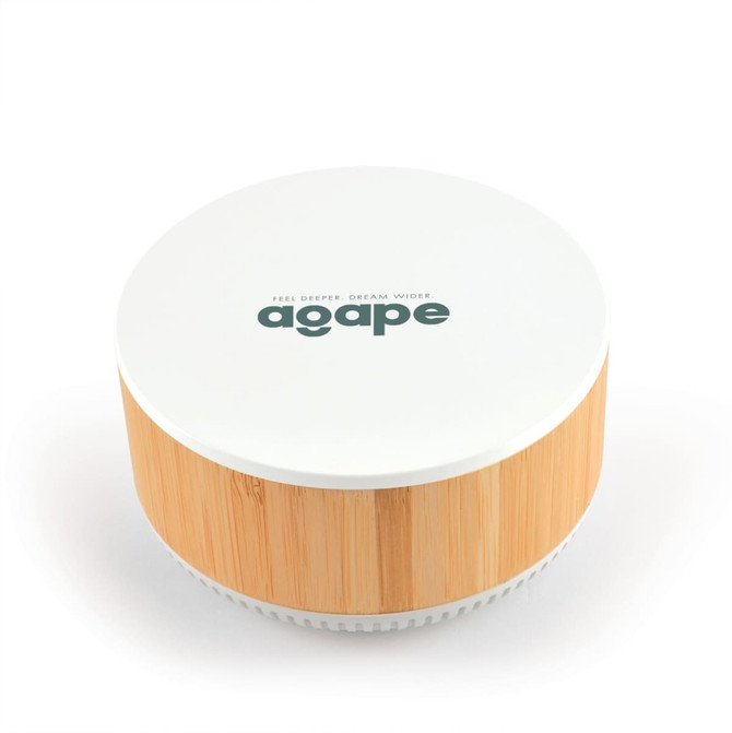 A round speaker and wireless charger with a white top and bamboo base, featuring a logo on the surface.