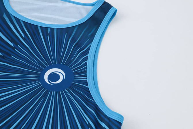 A blue sublimated singlet featuring a circular logo and a radial design pattern.