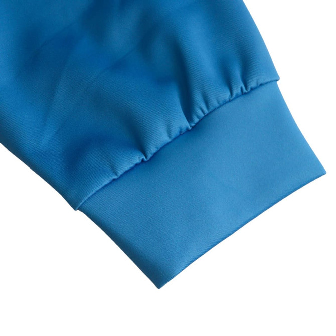 A close-up of the cuff of a blue polyester varsity jacket featuring a stretchy hem.