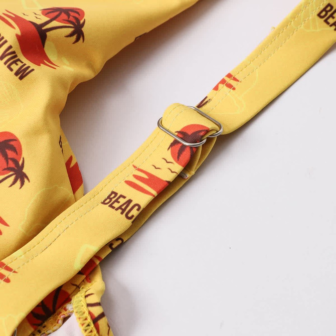 A yellow bikini top featuring a beach-themed print and an adjustable strap, with a logo detail.