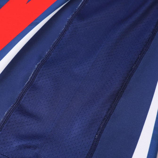 A close-up of a blue long-sleeved t-shirt featuring red and white accents, with a textured fabric. It has a logo.