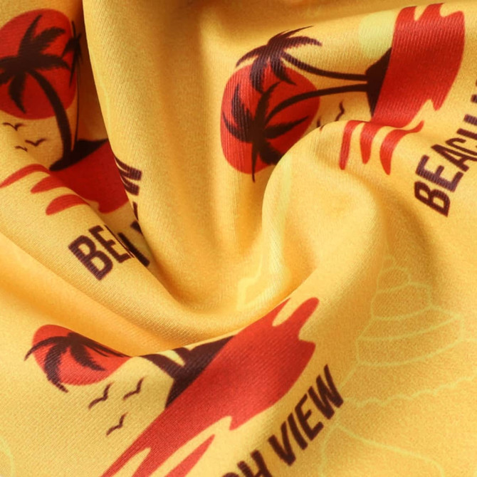 A yellow fabric featuring a beach scene with red palm trees and sunset graphics, showcasing a vibrant pattern.