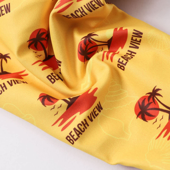 A yellow bikini bottom featuring a tropical print with palm trees and beach scenes, and a logo.