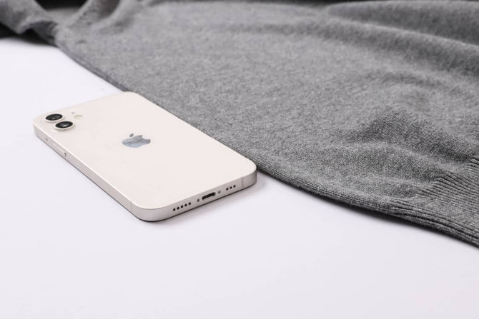 A grey unisex 100% cotton V-neck sweater beside a smartphone, featuring a logo on the phone.