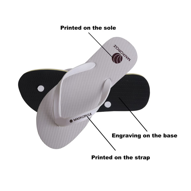 A pair of white rubber thongs with black accents, featuring engraved details on the sole and printed design on the strap.