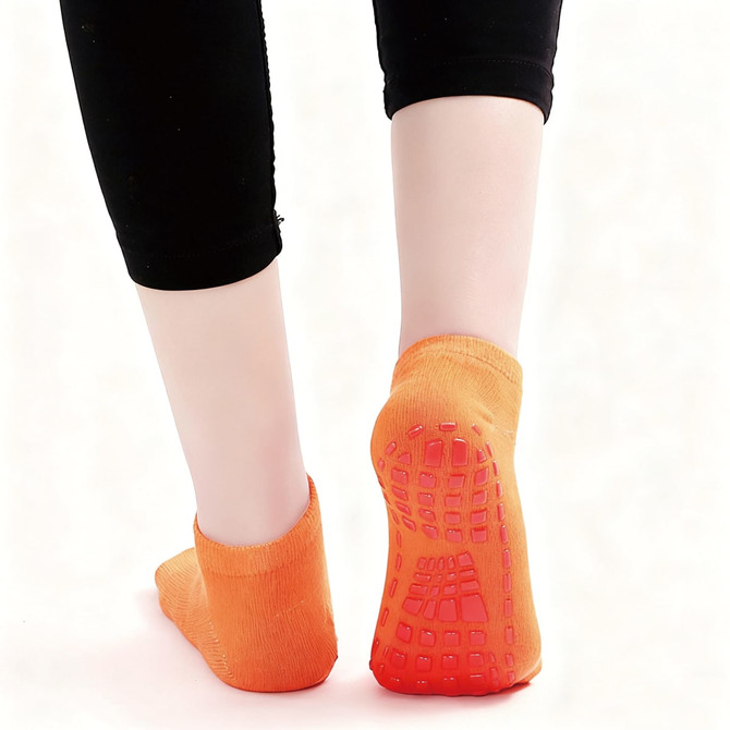 Low cut kids gripper socks in vibrant orange with textured soles, featuring a non-slip grip design.