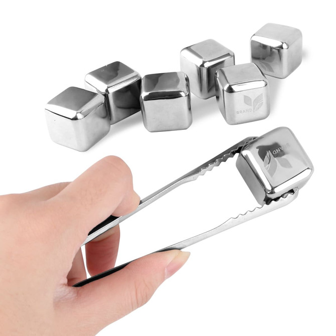 A hand using tongs to hold a stainless steel ice cube with several other cubes in the background.